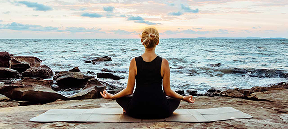 A woman meditating by the sea