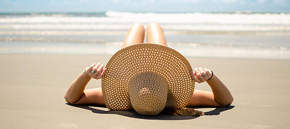 Woman in a hat lying on the beach