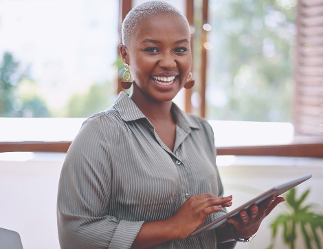 A woman smiles happily while holding her iPad.