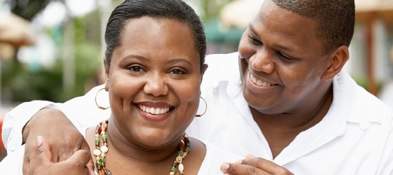 A woman smiles for the camera, as her husband looks at her adoringly.