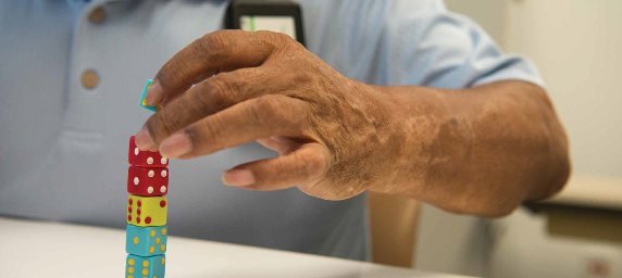 TIRR Memorial Hermann patient, Hector Alvarez, carefully stacks dice as part of physical therapy.