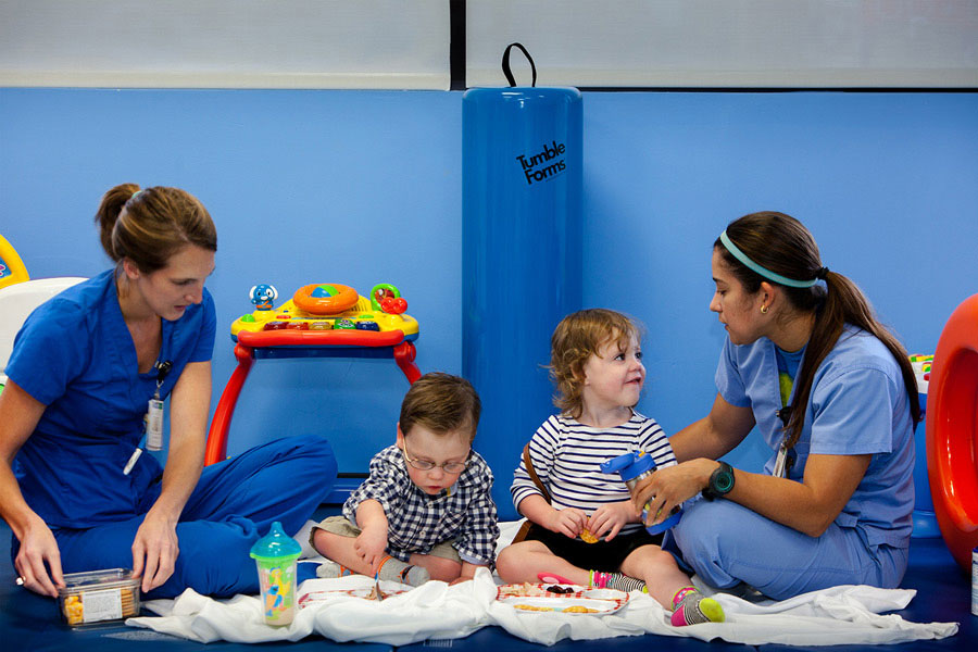 Two children eating with therapists