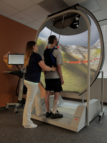 Patient using rehabilitation machine with therapist