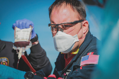 An on-scene Life Flight Paramedic holds a transfusion bag.