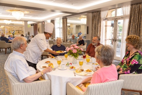 Residents of Memorial Hermann University Place dine together over fresh linens in the dining room.