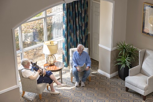 Residents of Memorial Hermann University Place sit talking in front of a picture window. 