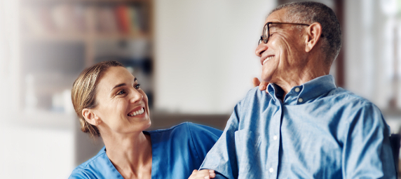 A man and his caregiver smile at each other.